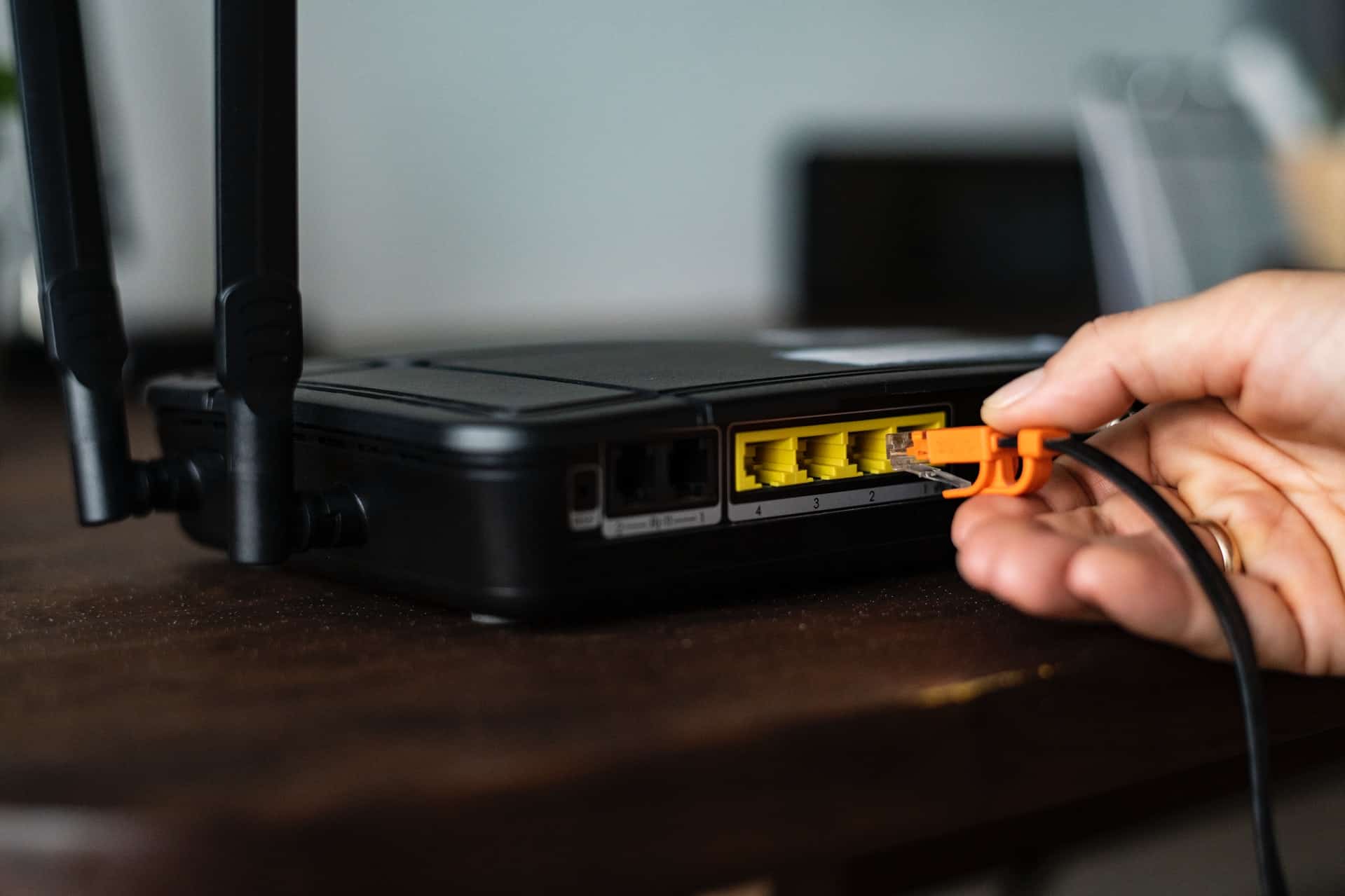 Close-up of hand plugging a cable into a wireless router